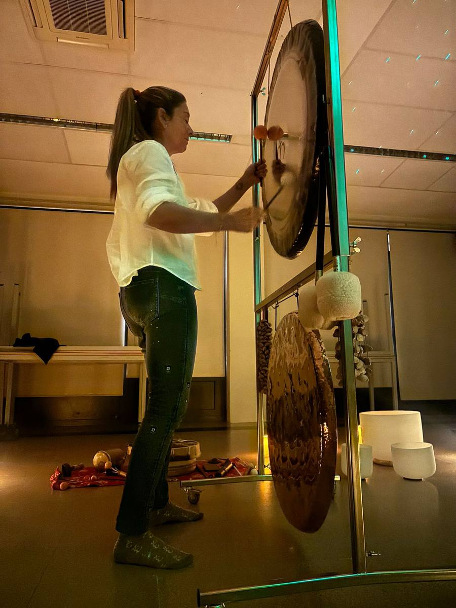Montse playing the gongs in a candlelit session