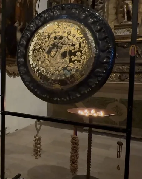 Detalle de un gong planetario dorado con velas encendidas en una iglesia
