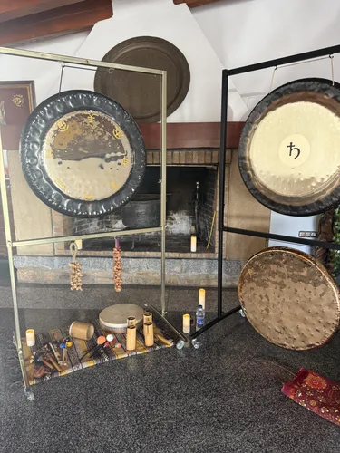 Tres gongs planetaris preparats al costat d'una xemeneia per a un bany de so a Lleida, amb tambor, koshi i espelmes