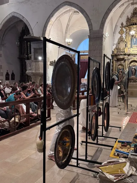 Sesión de gong en una iglesia barroca con público sentado y gongs planetarios